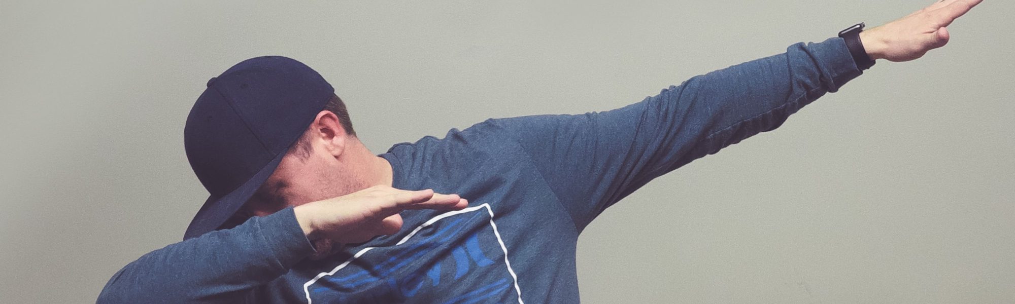 A person sporting a navy blue cap and long-sleeve shirt performs the dab dance move against a plain background, adding to the festive vibe as Circle 270 Media celebrates 5 years.