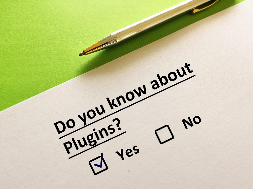 A survey question on paper asks, Do you know about website plugins? with checkboxes for Yes and No. The Yes box is checked. A pen rests on the green surface beside the paper.