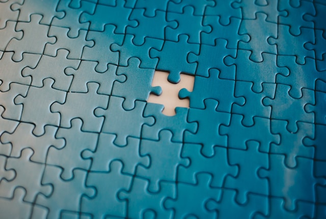A nearly completed blue jigsaw puzzle with one piece missing in the center, revealing a white surface beneath—symbolizing an unresolved business problem awaiting a solution with a podcast.