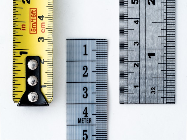 Close-up of three measuring tools—yellow tape measure, white flexible ruler, and silver metal ruler—placed on a white background, visually echoing the precision needed for tracking podcast metrics.